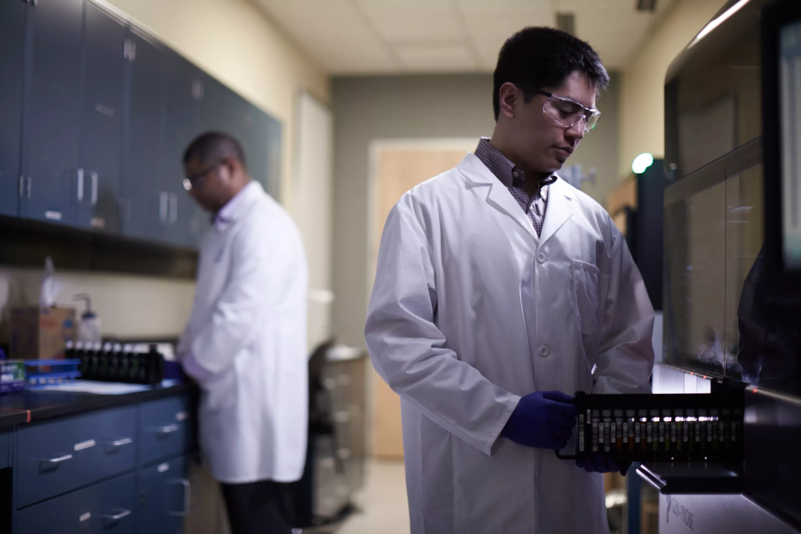Técnico de laboratório a colocar um tabuleiro de frascos no sistema médico