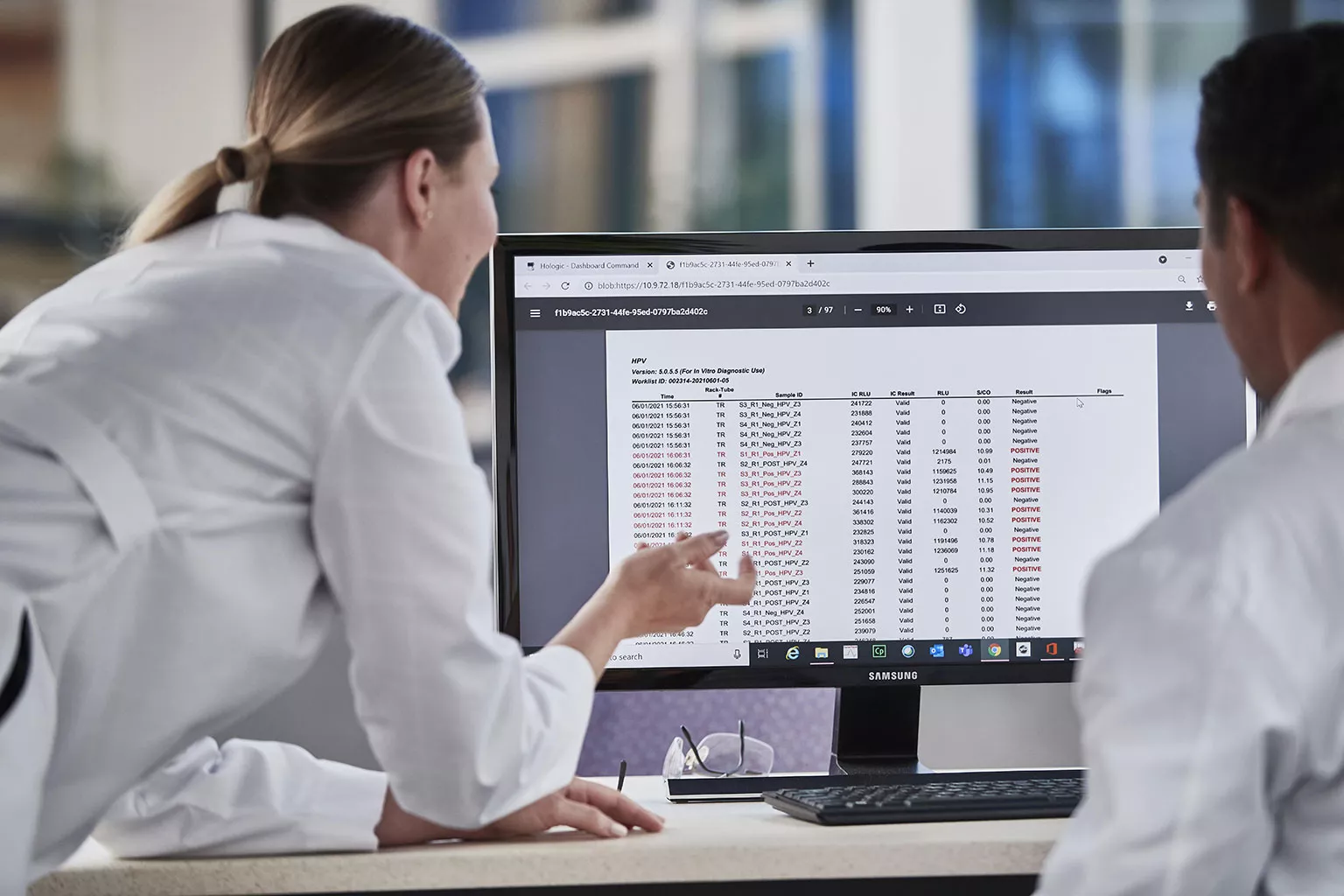 Imagem de técnicos de laboratório a olhar para dados no monitor num laboratório.