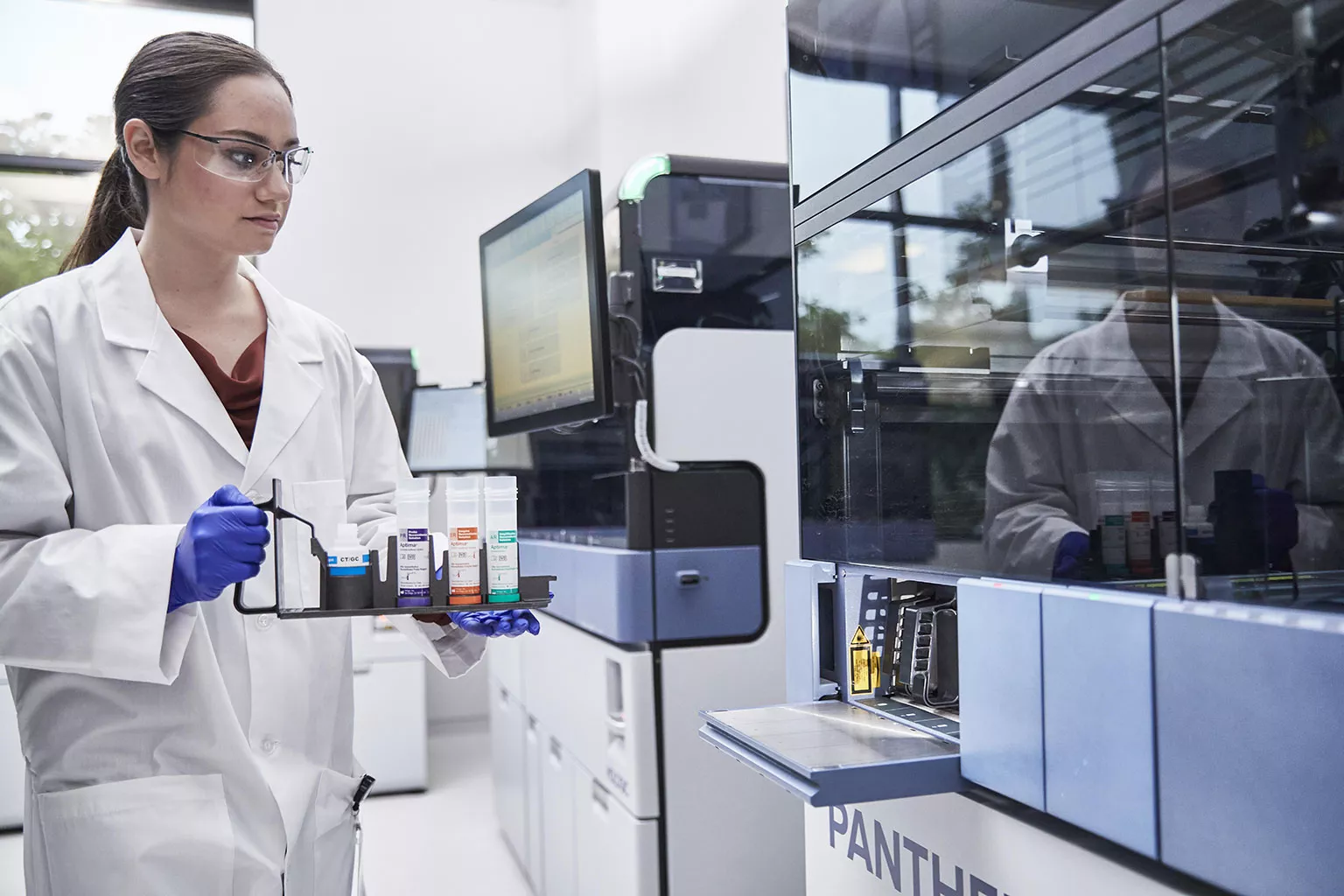 Técnico de laboratório a segurar um tabuleiro de tubos junto ao sistema Panther®.