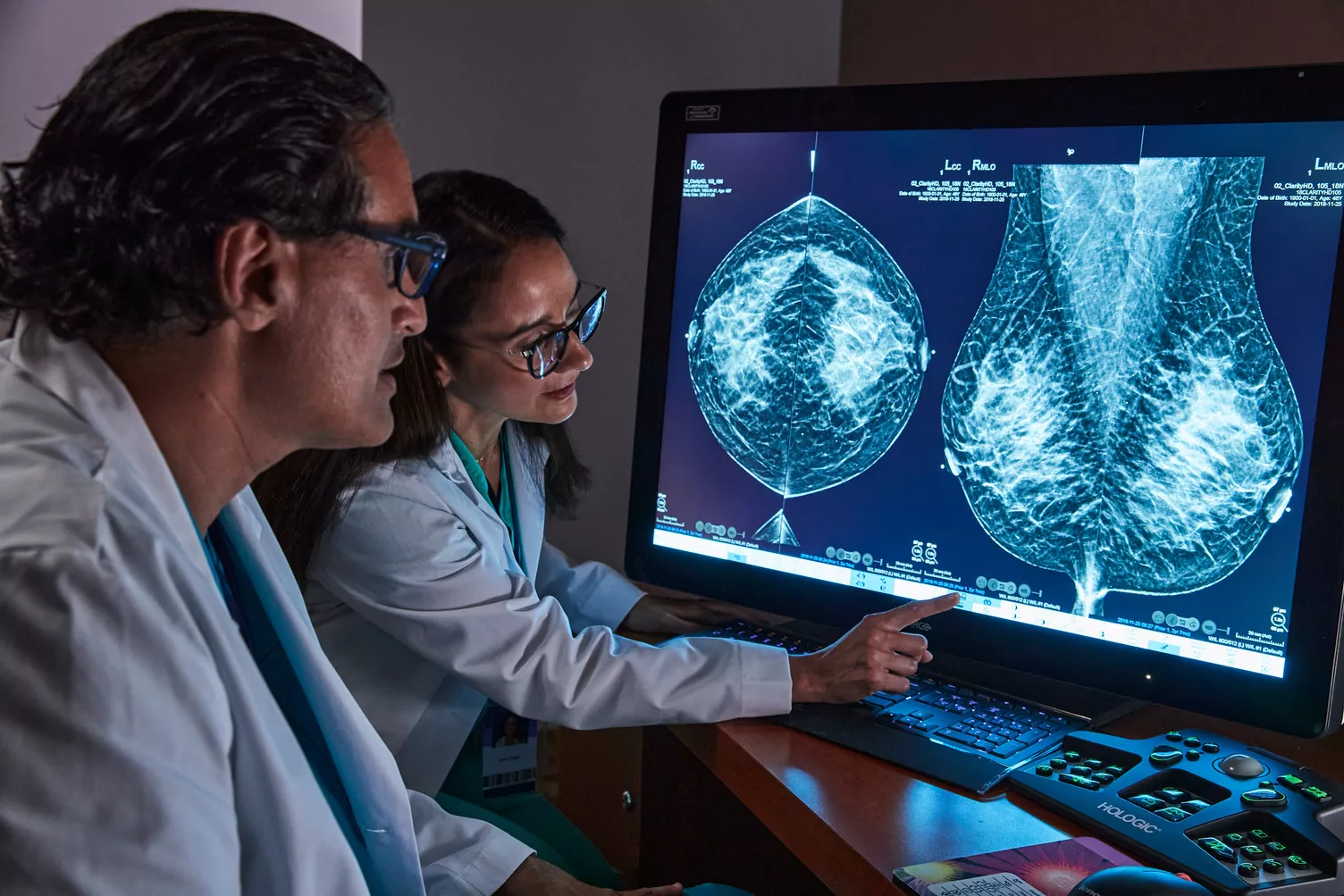 Profissional de saúde aponta para mamografia no monitor