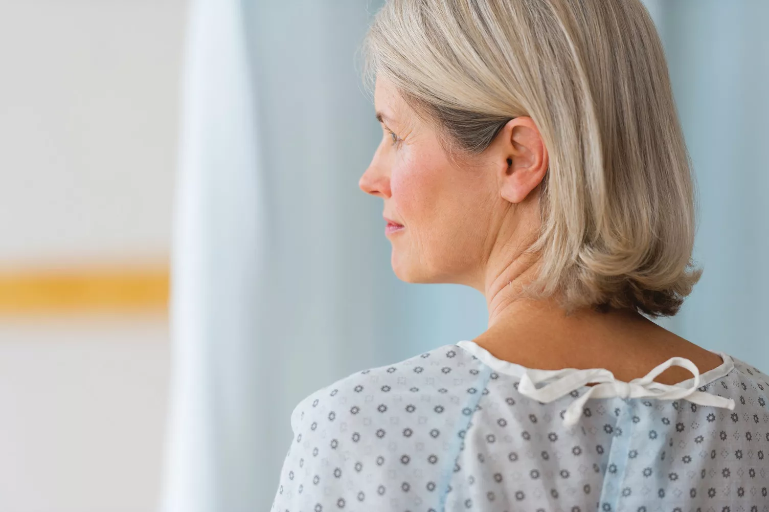 Mulher madura a olhar para a esquerda e a usar uma bata hospitalar