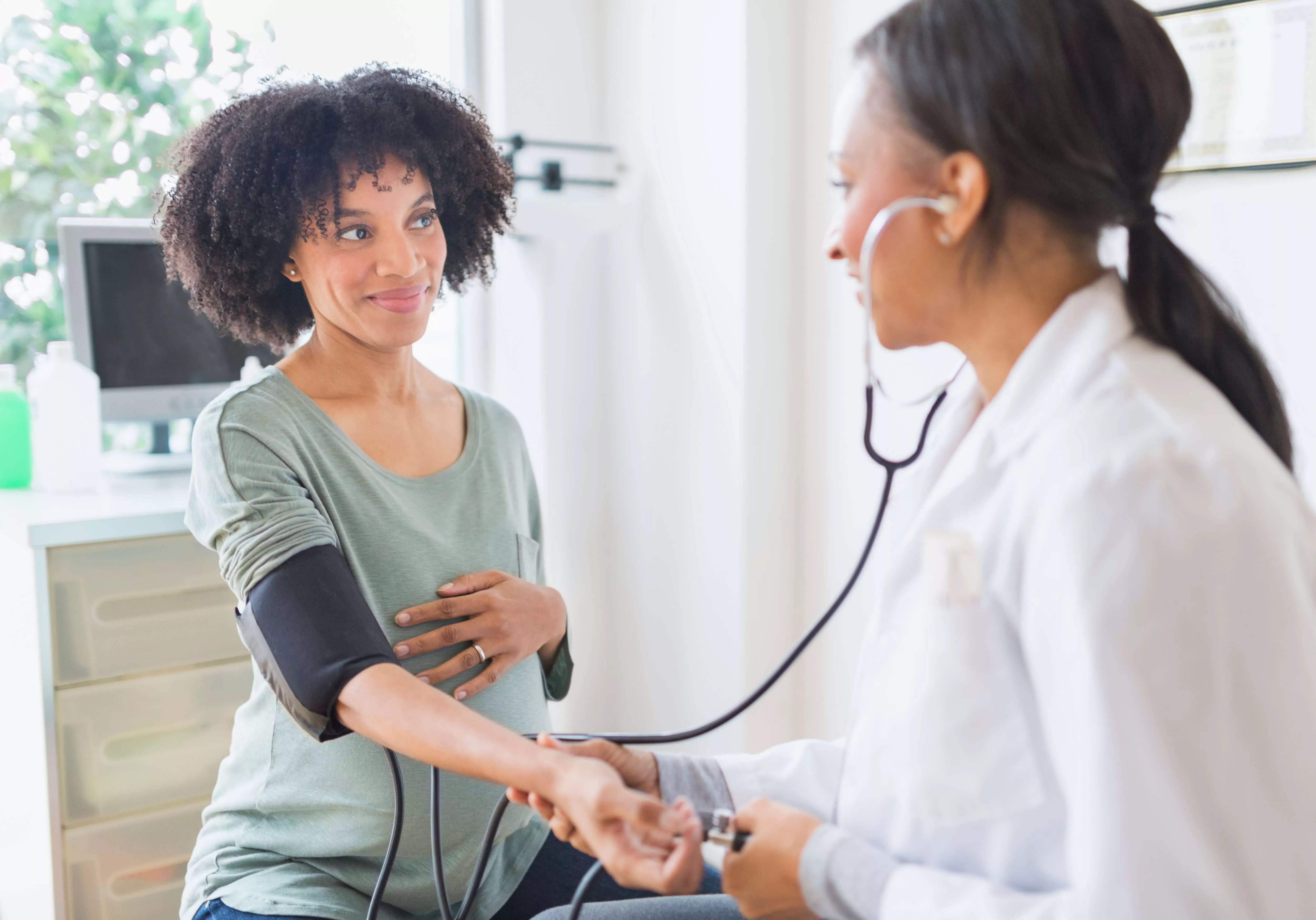Médica a utilizar o estetoscópio no braço de uma paciente.