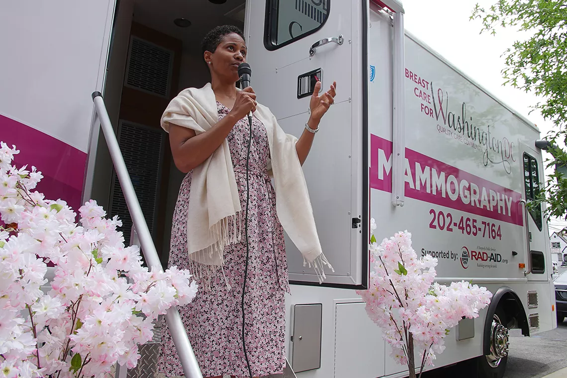 Mulher negra a discursar em frente ao autocarro de mamografia móvel (o MobileMammo)