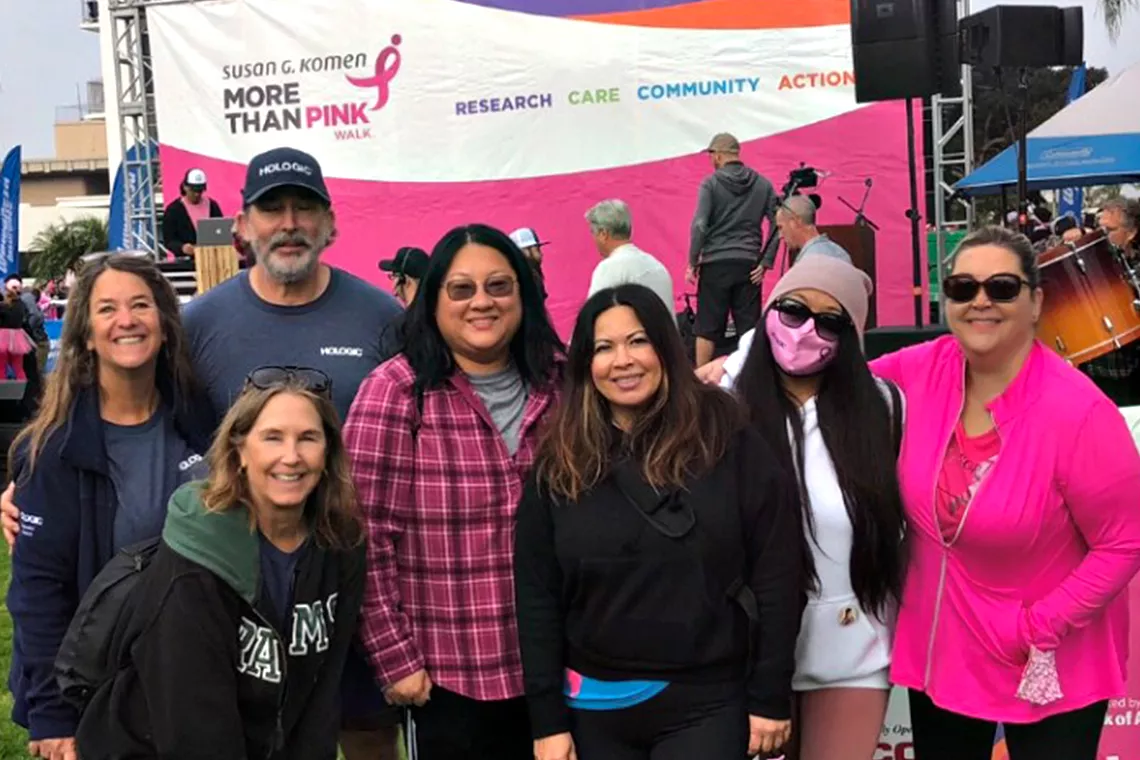 Foto de grupo de homens e mulheres a sorrir durante a Corrida Susan G. Komen, uma Corrida pela Cura