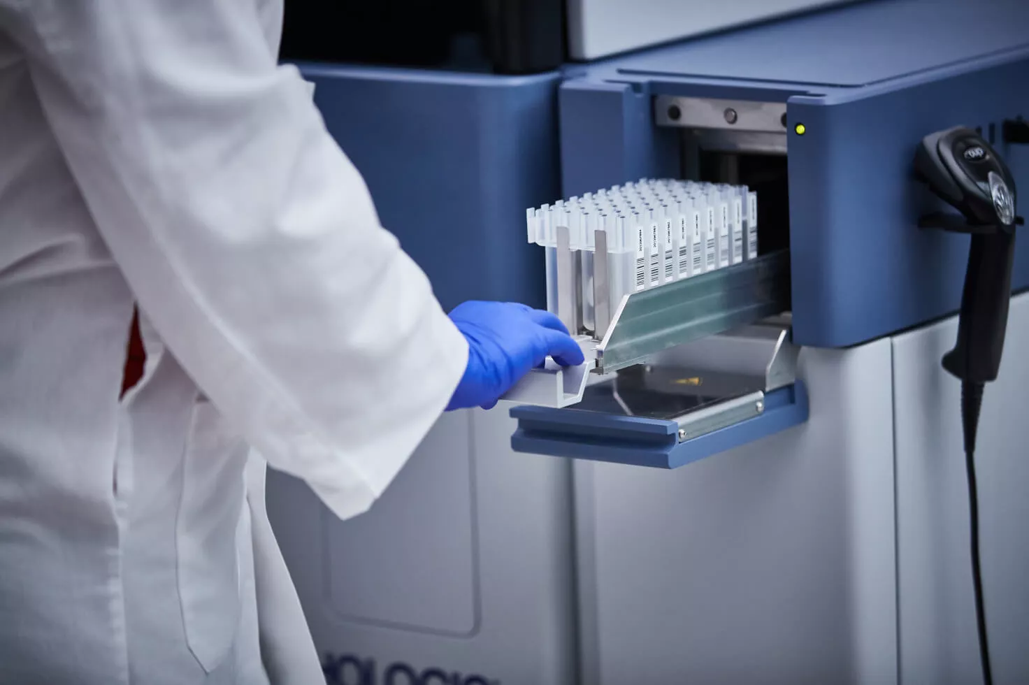Técnico de laboratório a introduzir tabuleiro de frascos no sistema médico