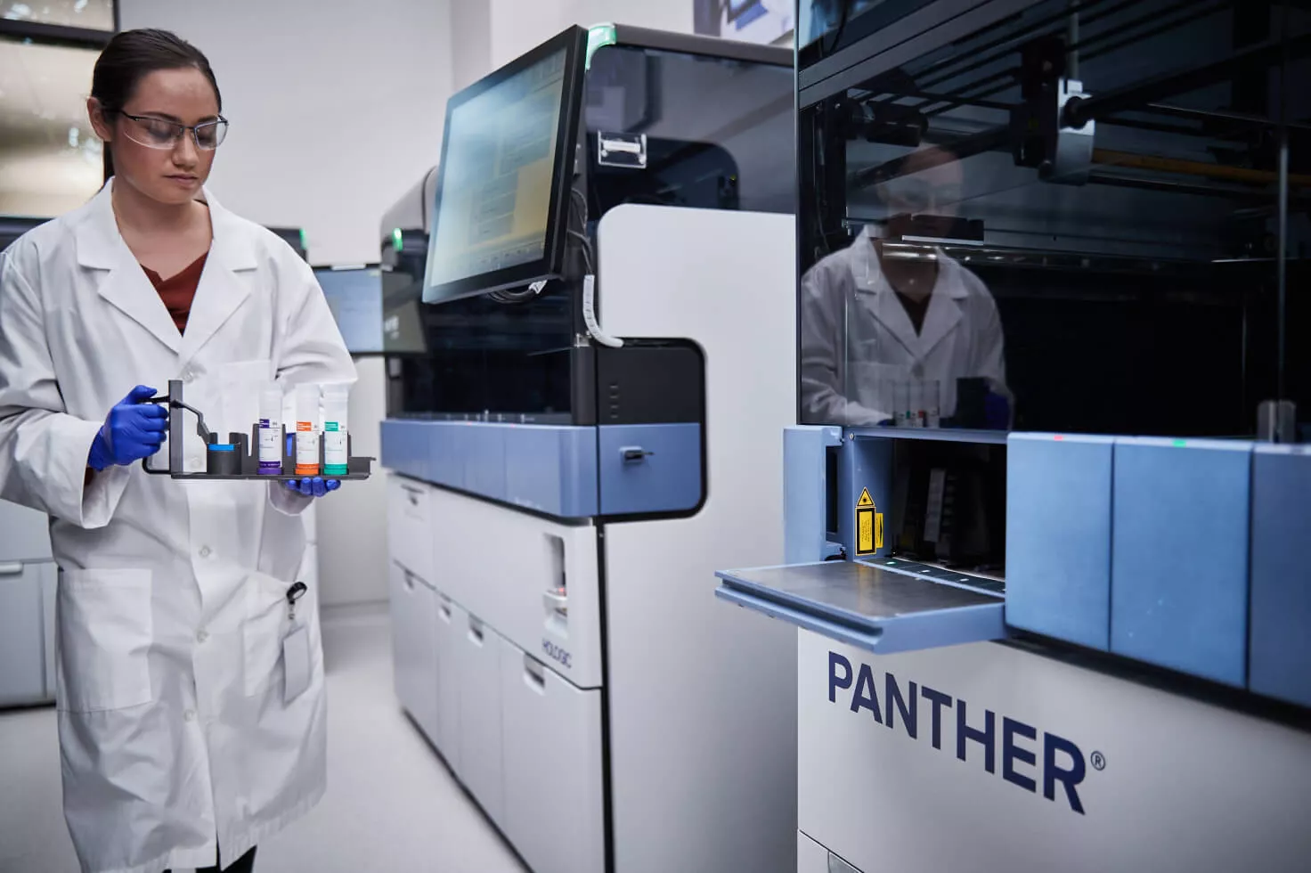 Técnico de laboratório a transportar um tabuleiro de frascos num laboratório