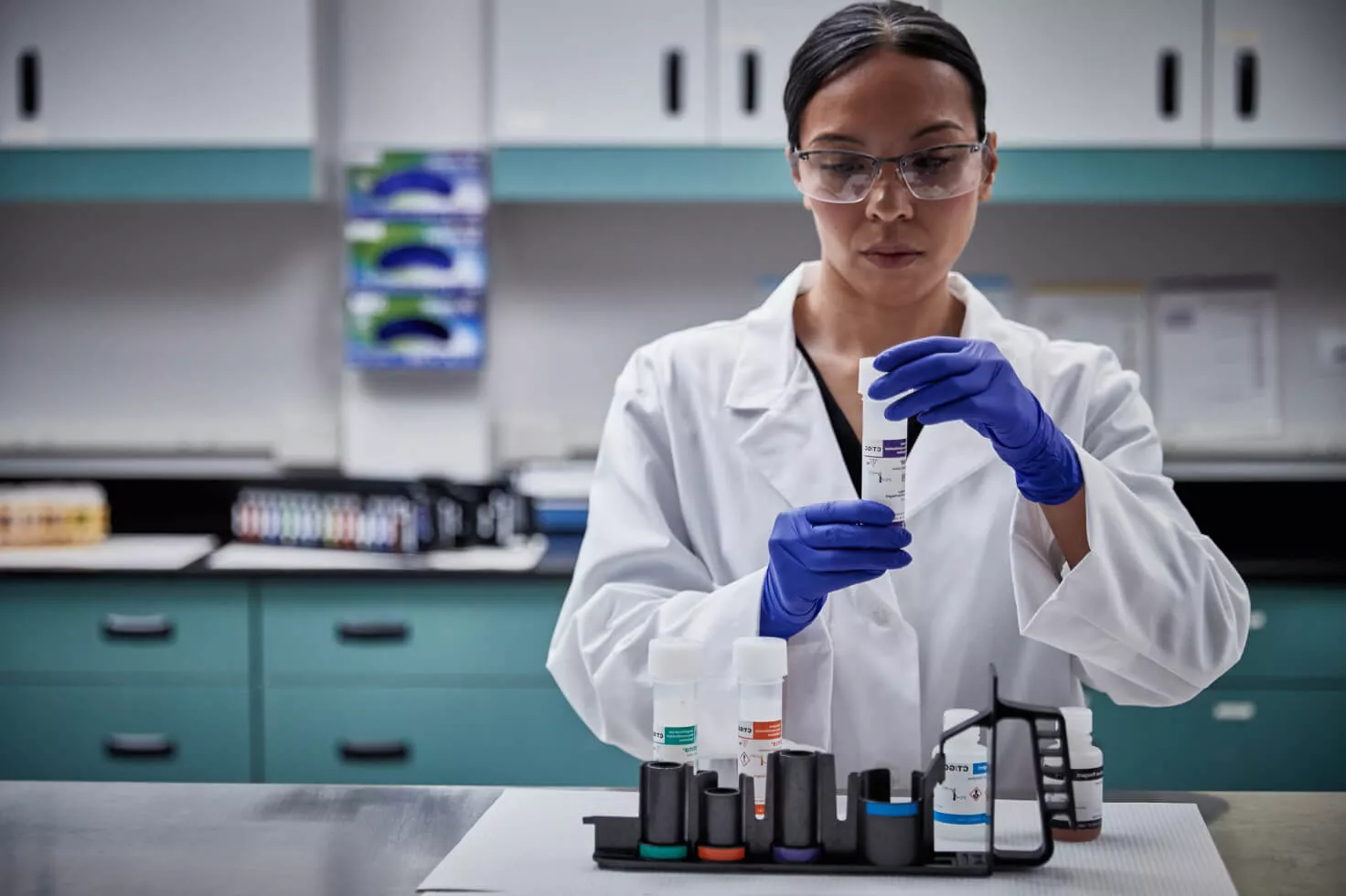 Técnica laboratorial a segurar um kit de colheita com zaragatoa em contexto laboratorial